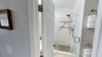 Bathroom with pedestal sink basin, large walk-in shower stall with grab rail